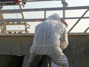 addetto toglie parti di eternit da una copertura per lo smaltimento